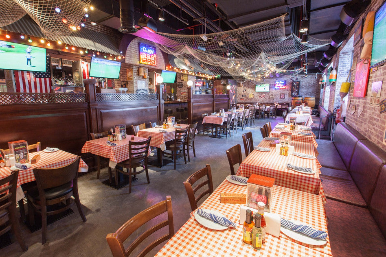Inside CLAW BBQ Dubai — string lights, neon and gingham tables